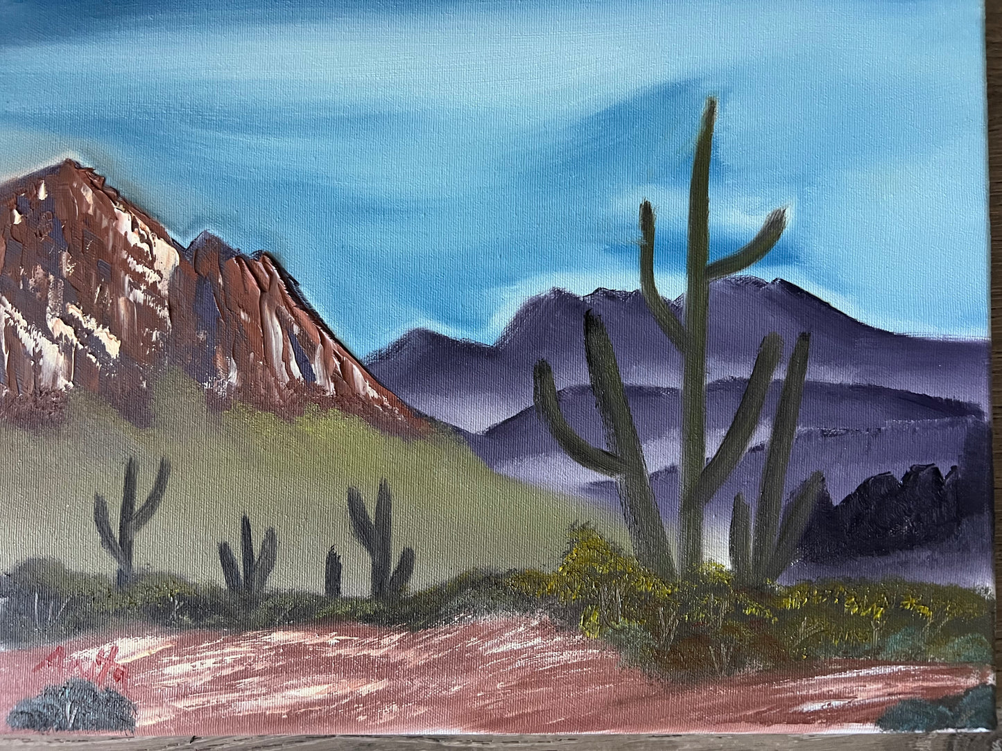 Painting of a desert landscape with mountains and cacti